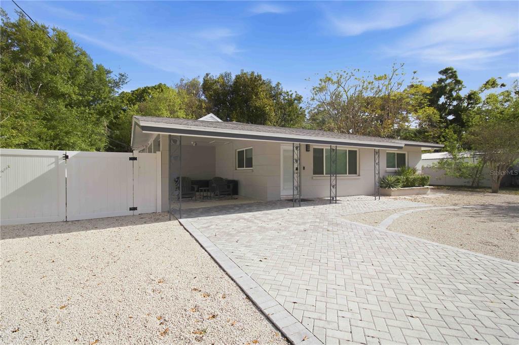 A single-story house features a paved driveway, a covered carport, and a white vinyl fence — 2545 BROWNING STREET, SARASOTA, FL