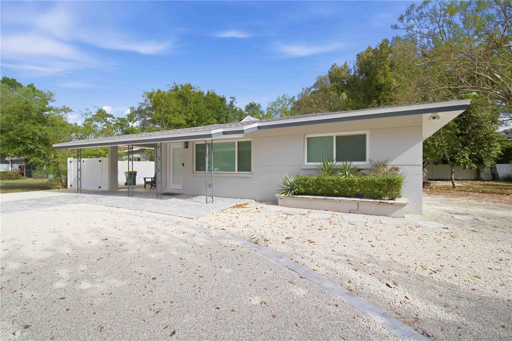 A single-story house with a gravel driveway, a carport, and a front garden bed — 2545 BROWNING STREET, SARASOTA, FL