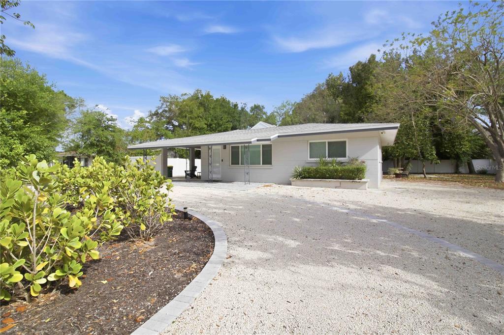A single-story house with a gravel driveway, a carport, and a landscaped front yard — 2545 BROWNING STREET, SARASOTA, FL