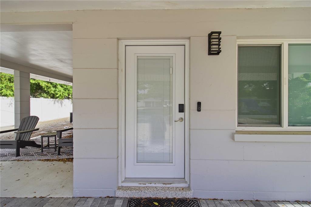 A white exterior door with an integrated window sits beside a window and wall light — 2545 BROWNING STREET, SARASOTA, FL