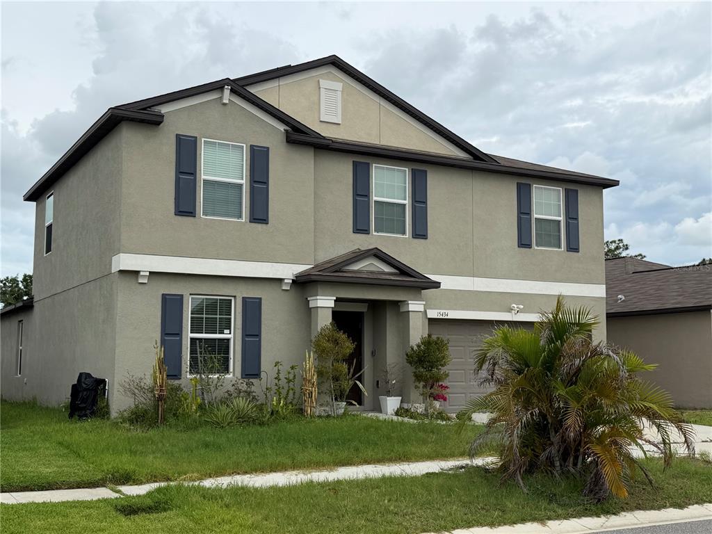 A two-story suburban house with a gray stucco exterior, dark shutters, and a front-facing garage — 15434 MILLER CREEK DRIVE, SUN CITY CENTER, FL