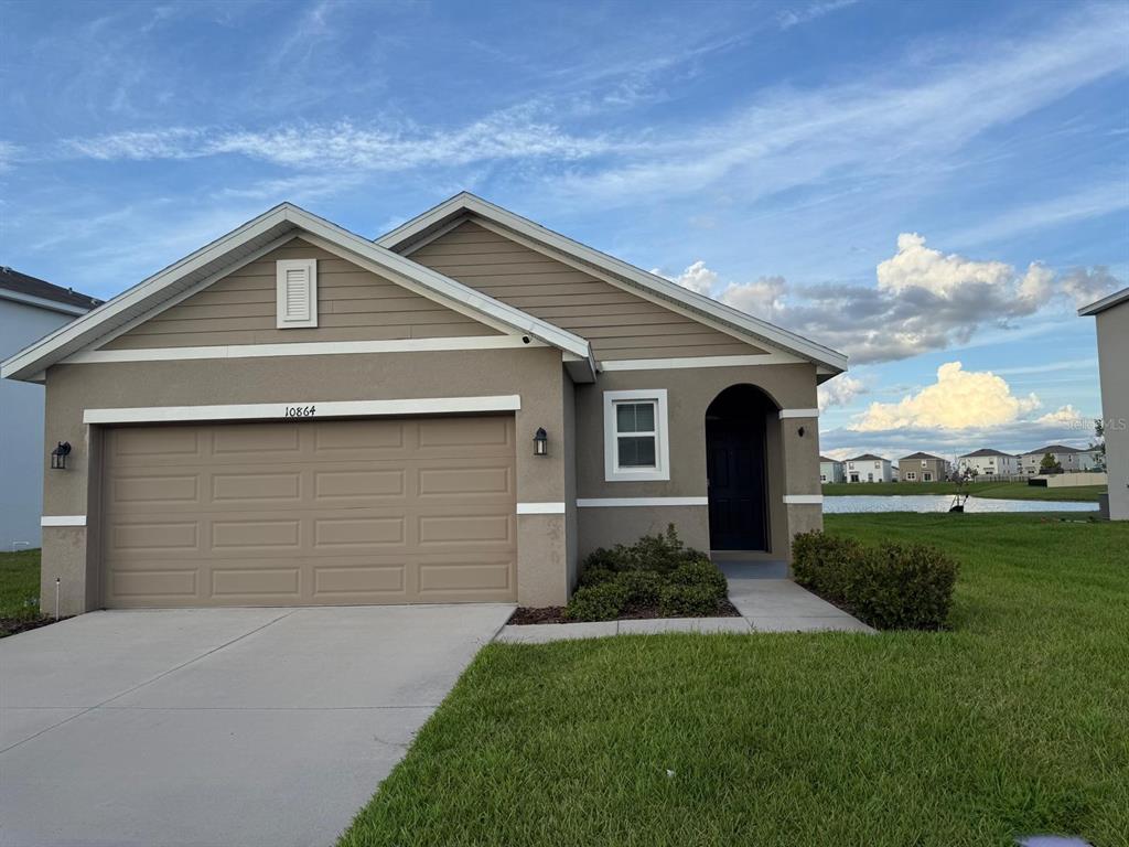 A single-story house with a tan stucco exterior, a two-car garage, and a front entryway — 10864 PENNY GALE LOOP, SAN ANTONIO, FL