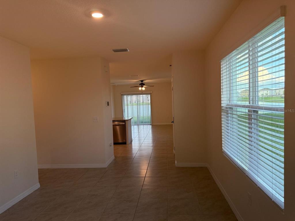 A view from a tiled room looking toward a kitchen and a sliding glass door — 10864 PENNY GALE LOOP, SAN ANTONIO, FL