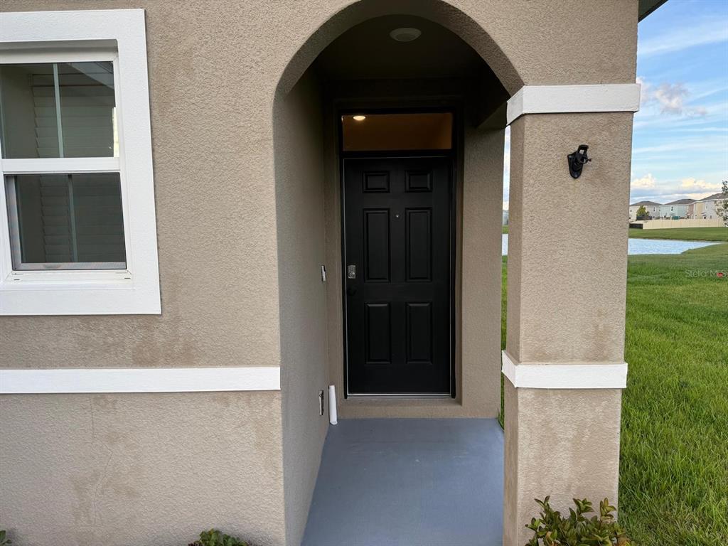 A tan stucco house exterior features a black front door under an arched entryway — 10864 PENNY GALE LOOP, SAN ANTONIO, FL