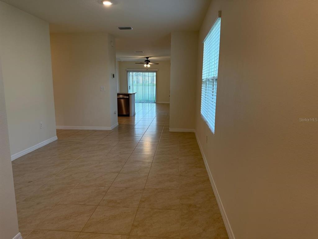 An open-concept living area features light-colored tile flooring and a view toward the kitchen — 10864 PENNY GALE LOOP, SAN ANTONIO, FL