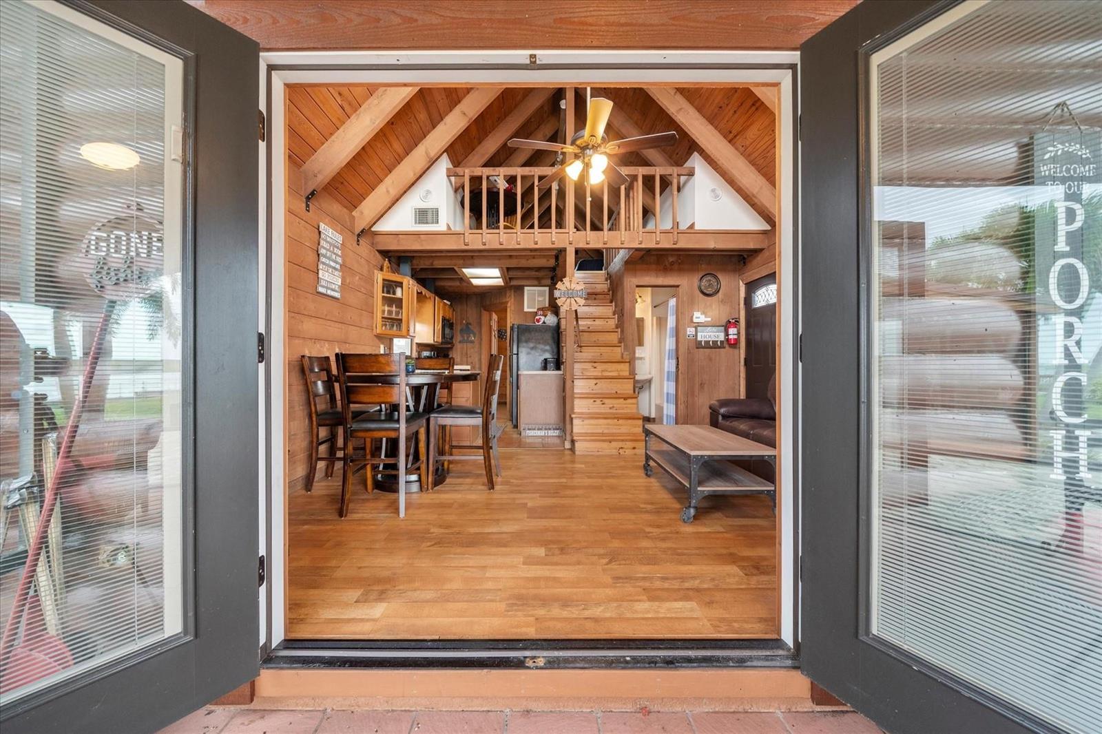 A view from a doorway into a rustic cabin living area with a wooden loft — 8344 US Highway 441, Okeechobee FL 34974, OKEECHOBEE, FL