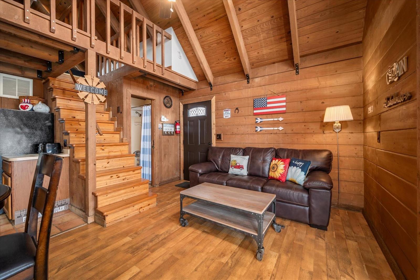 A rustic living room features wood walls, a brown leather sofa, and a wooden staircase — 8344 US Highway 441, Okeechobee FL 34974, OKEECHOBEE, FL
