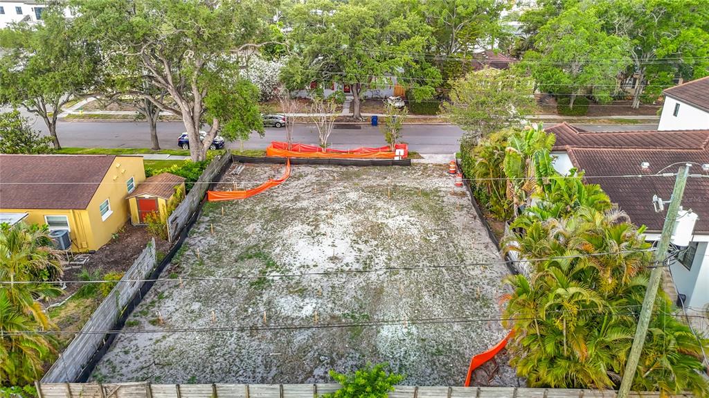 An aerial view shows a vacant, fenced residential lot with survey stakes in the ground — 329 COLUMBIA DRIVE, TAMPA, FL