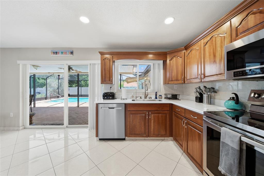 A kitchen with wood cabinets, stainless steel appliances, white countertops, and a sliding glass door — 1403 GARDEN AVENUE, TARPON SPRINGS, FL