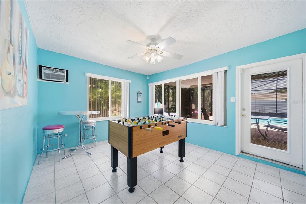 A game room with light blue walls, tile flooring, a foosball table, and a patio door — 1403 GARDEN AVENUE, TARPON SPRINGS, FL