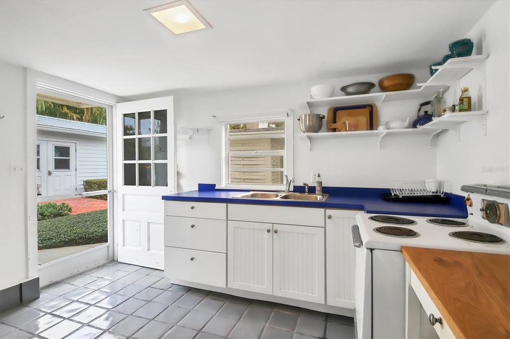 A kitchen with white cabinets, a blue countertop, open shelving, and a glass-paned door — 241 GILCHRIST AVENUE UNIT F, BOCA GRANDE, FL