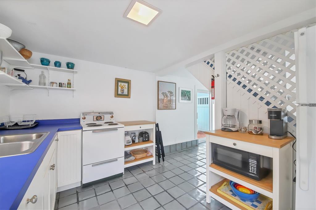 A kitchen features blue countertops, white cabinetry, a white stove, and gray tiled flooring — 241 GILCHRIST AVENUE UNIT F, BOCA GRANDE, FL