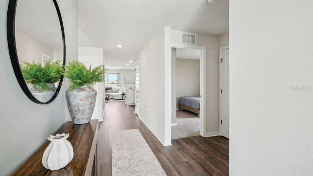 A hallway with wood-look flooring leads to a living area and a bedroom — 746 GREENWAY BOULEVARD, LAKE WALES, FL