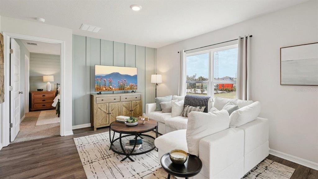 A living room features a light blue accent wall, white sofa, and wood-toned media console — 746 GREENWAY BOULEVARD, LAKE WALES, FL