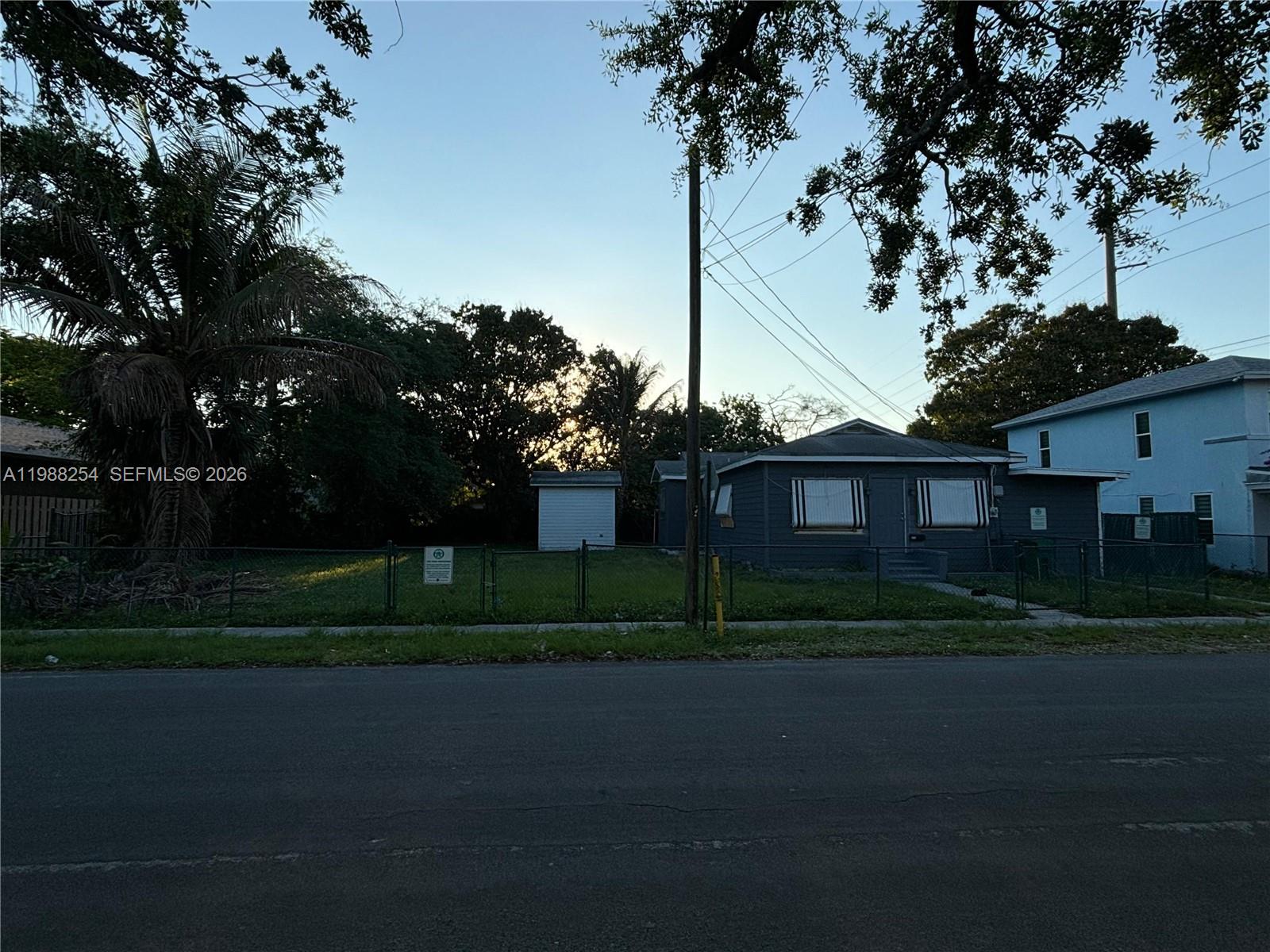 A gray house sits next to a fenced vacant lot with a small shed — 214 SW 1st Ave, Dania Beach FL 33004, DANIA BEACH, FL