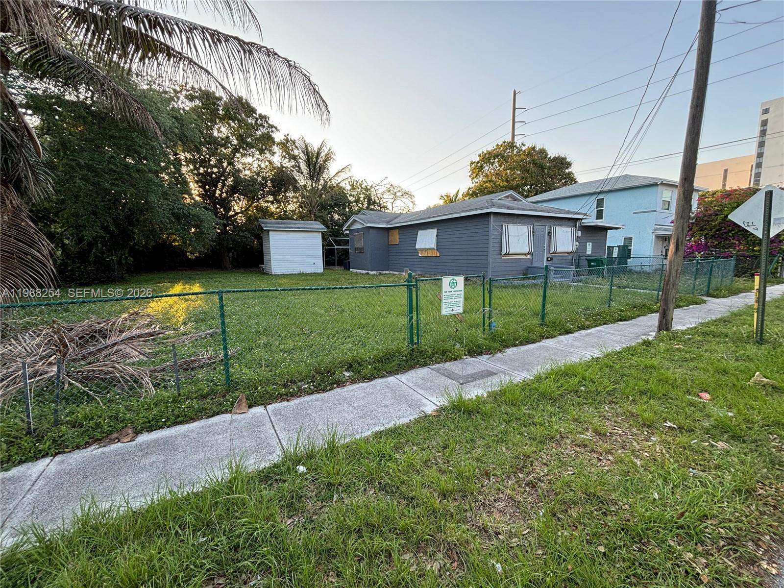 A gray single-story house with a fenced yard and a small shed sits on a lot — 214 SW 1st Ave, Dania Beach FL 33004, DANIA BEACH, FL