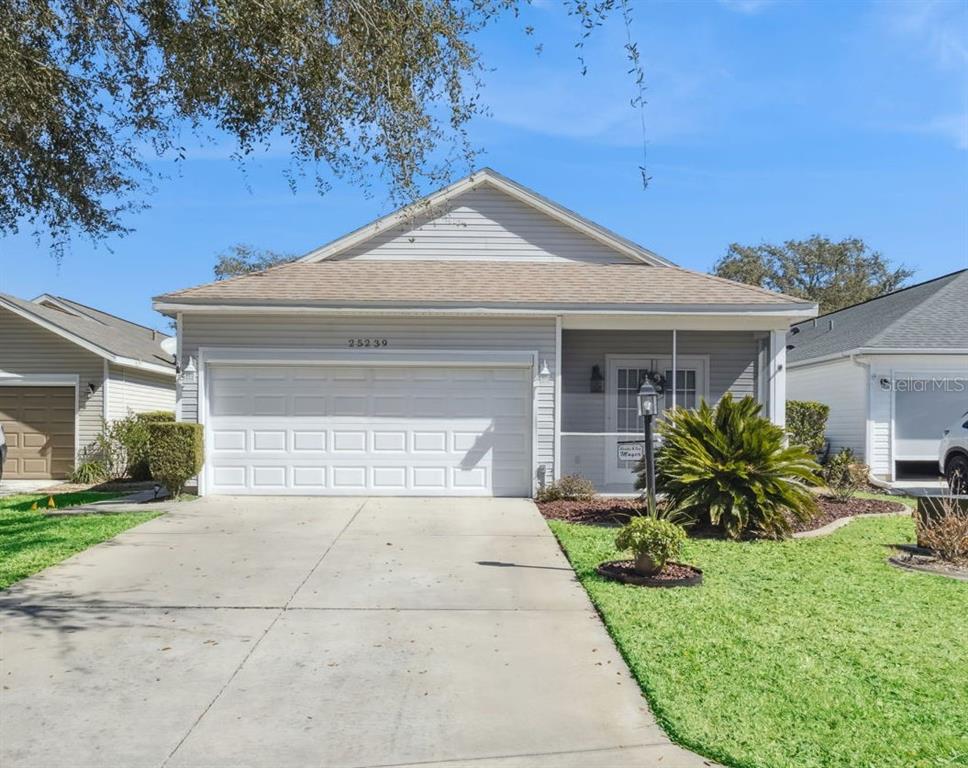 A single-story house with light gray siding, a two-car garage, and a screened front porch — 25239 CRANES ROOST CIRCLE, LEESBURG, FL