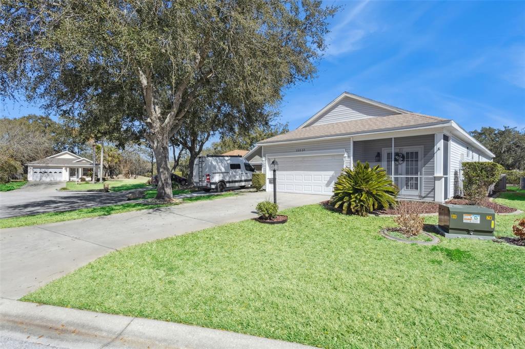 A single-story house with a white garage, gray siding, and a screened front porch — 25239 CRANES ROOST CIRCLE, LEESBURG, FL