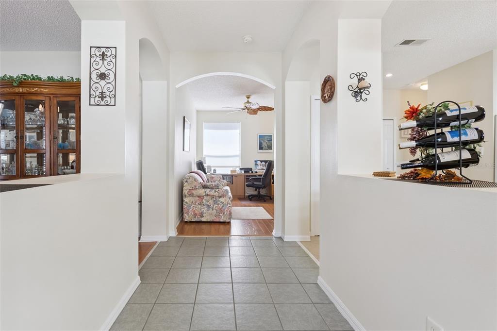 A tiled entryway leads through an arched opening into a room with a desk and sofa — 25239 CRANES ROOST CIRCLE, LEESBURG, FL