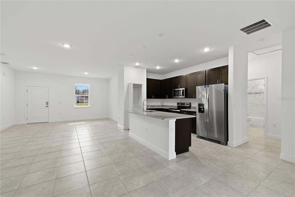 A kitchen with dark cabinets, stainless steel appliances, and a granite island in an open room — 15322 SW 50TH COURT ROAD, OCALA, FL