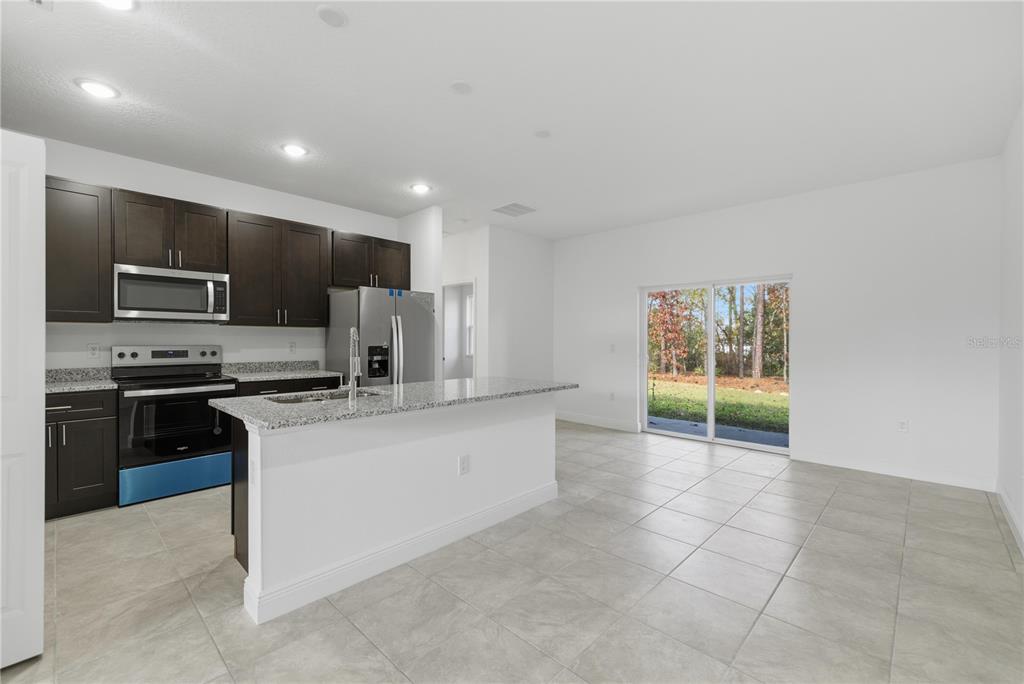 A kitchen with dark cabinets, granite countertops, stainless steel appliances, and tile flooring — 15322 SW 50TH COURT ROAD, OCALA, FL