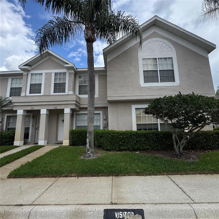 A two-story tan townhouse with a palm tree and a small tree in the front — 306 KENSINGTON LAKE CIRCLE, BRANDON, FL
