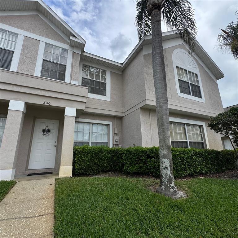 A two-story stucco townhouse exterior with a palm tree, front door, and manicured hedges — 306 KENSINGTON LAKE CIRCLE, BRANDON, FL