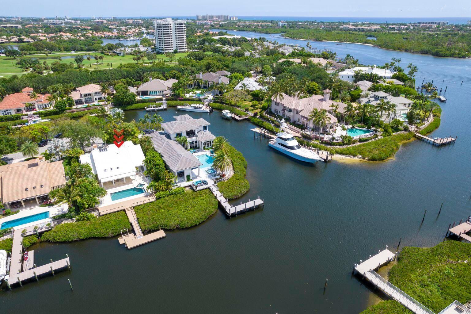 An aerial view of a waterfront home with a pool, private dock, and docked boat — 215 Island Drive, Jupiter FL 33477, JUPITER, FL