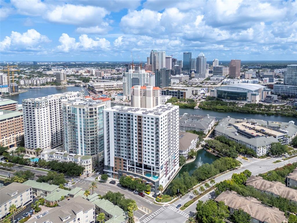 An aerial view shows a high-rise apartment building surrounded by city buildings and waterways — 450 KNIGHTS RUN AVENUE UNIT 1503, TAMPA, FL