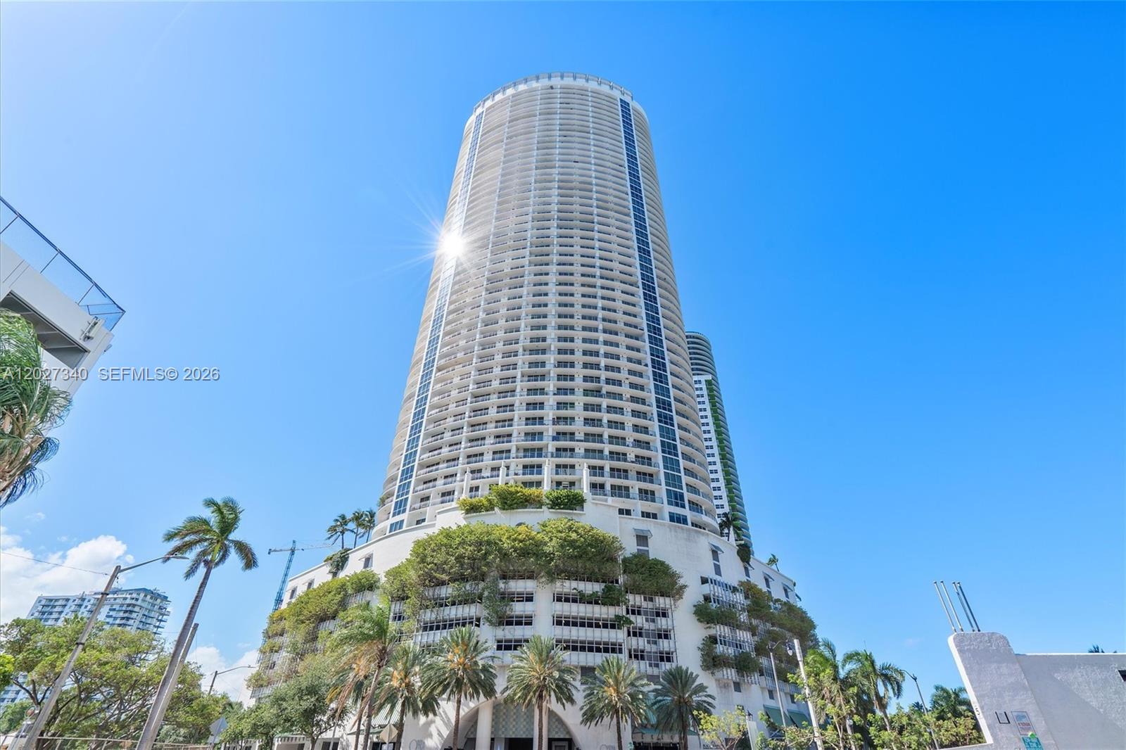 A tall, cylindrical residential skyscraper features a multi-level parking podium covered in lush greenery — 1750 N Bayshore Dr # 3106, Miami FL 33132, MIAMI, FL