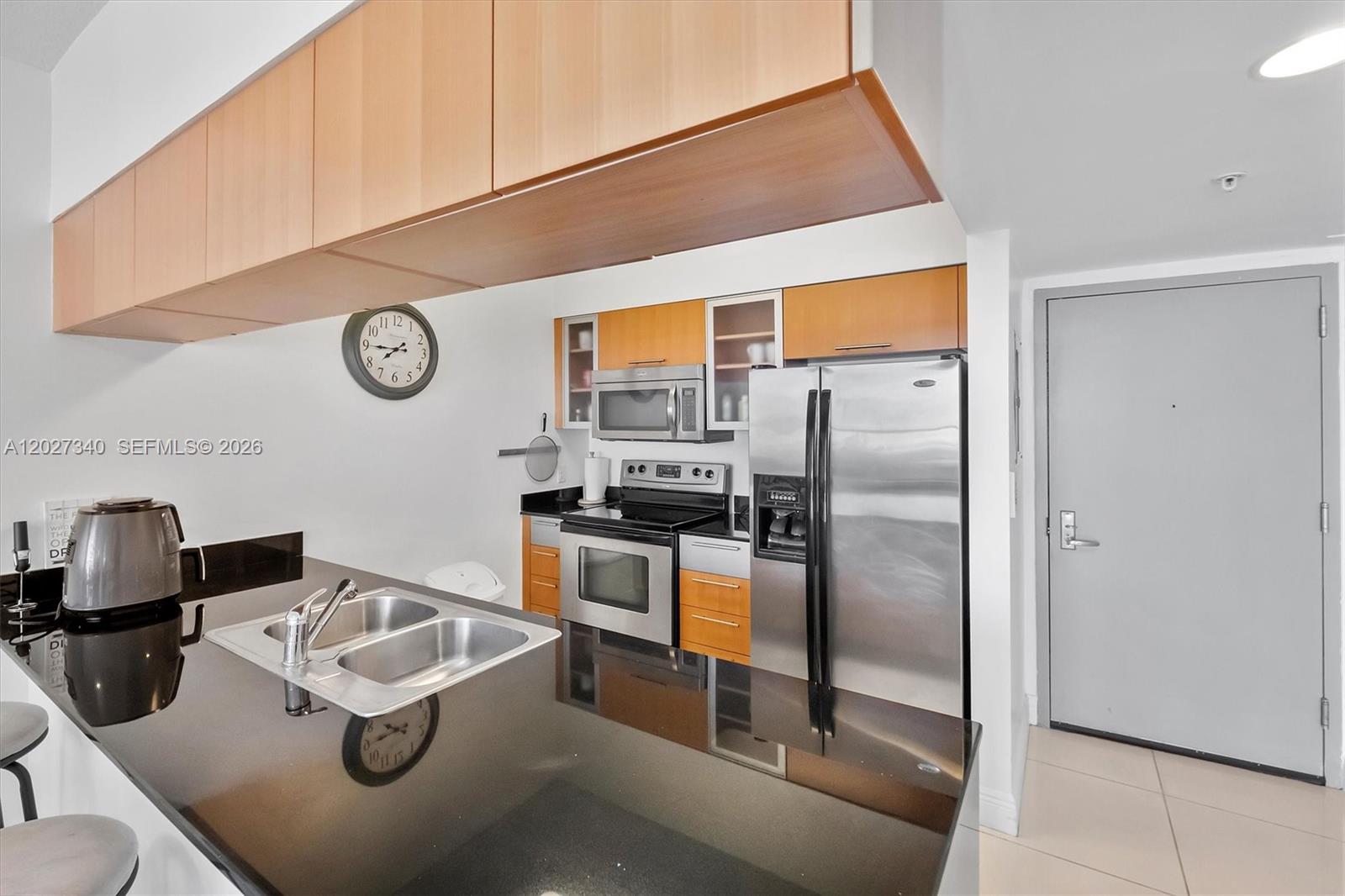A kitchen features black countertops, stainless steel appliances, and light wood cabinetry — 1750 N Bayshore Dr # 3106, Miami FL 33132, MIAMI, FL