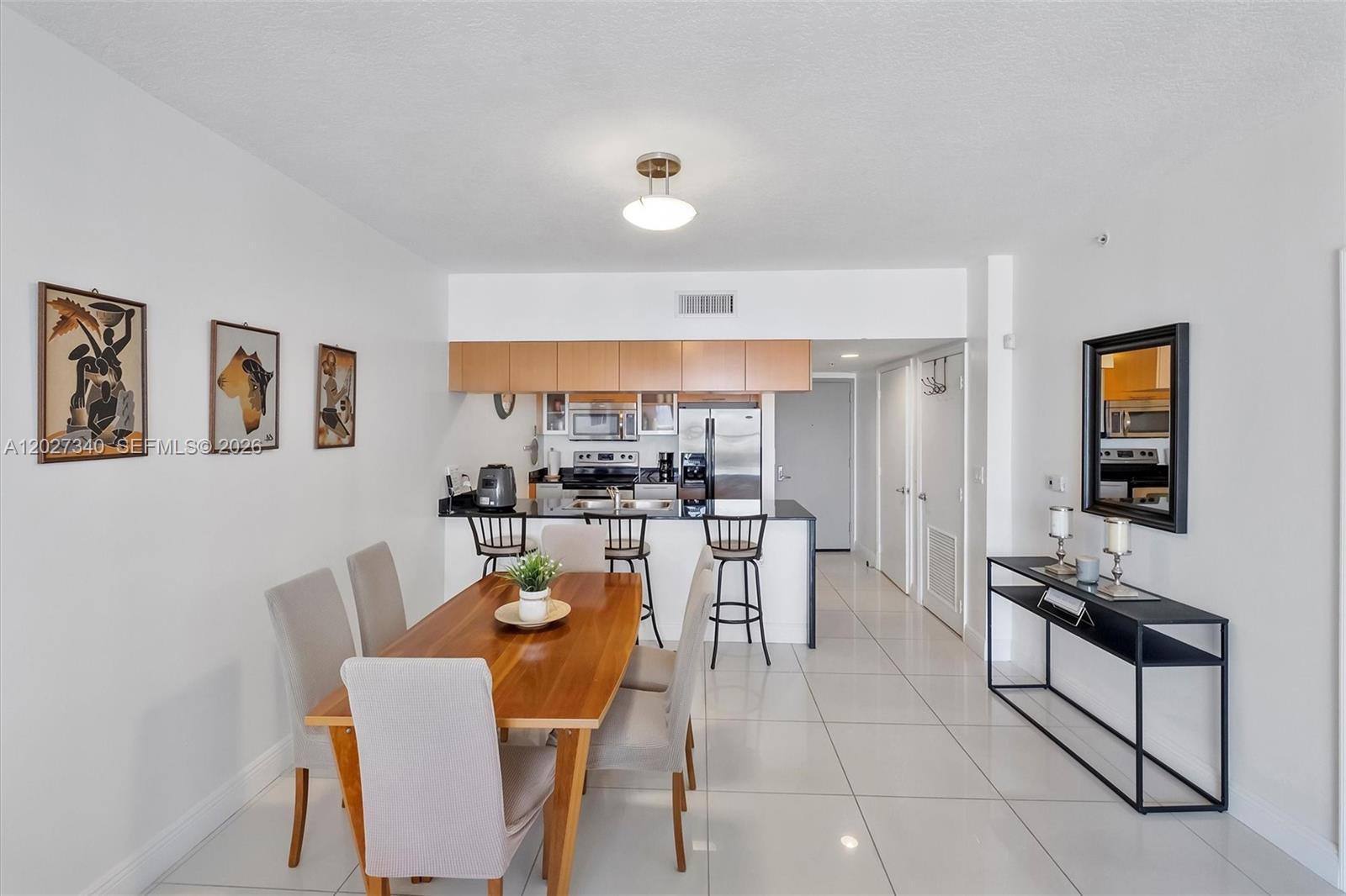 A dining area with a wooden table and chairs sits adjacent to an open kitchen — 1750 N Bayshore Dr # 3106, Miami FL 33132, MIAMI, FL
