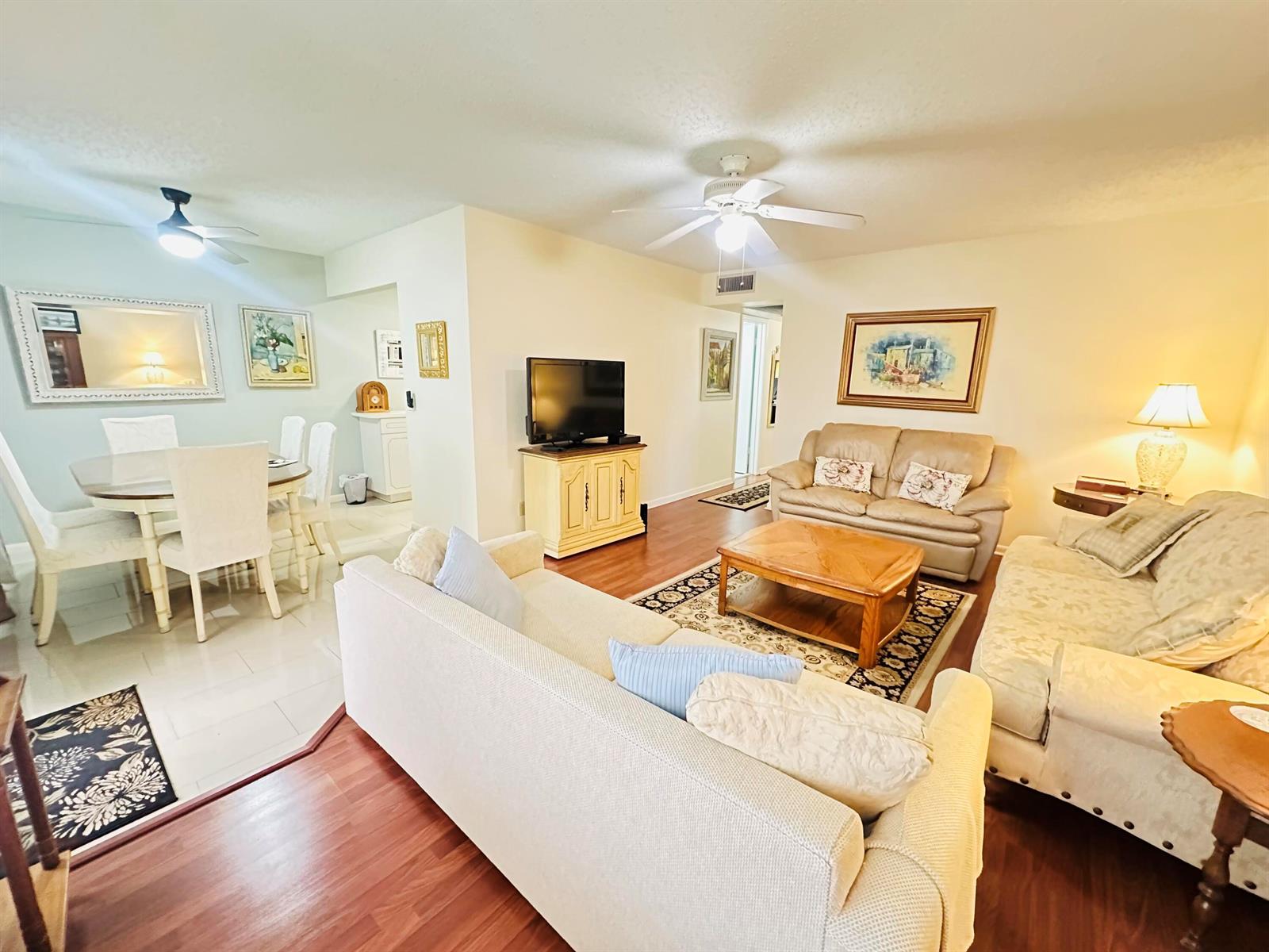A living room and dining area feature wood-look flooring, neutral furniture, and ceiling fans — 174 Durham C, Deerfield Beach FL 33442, DEERFIELD BEACH, FL