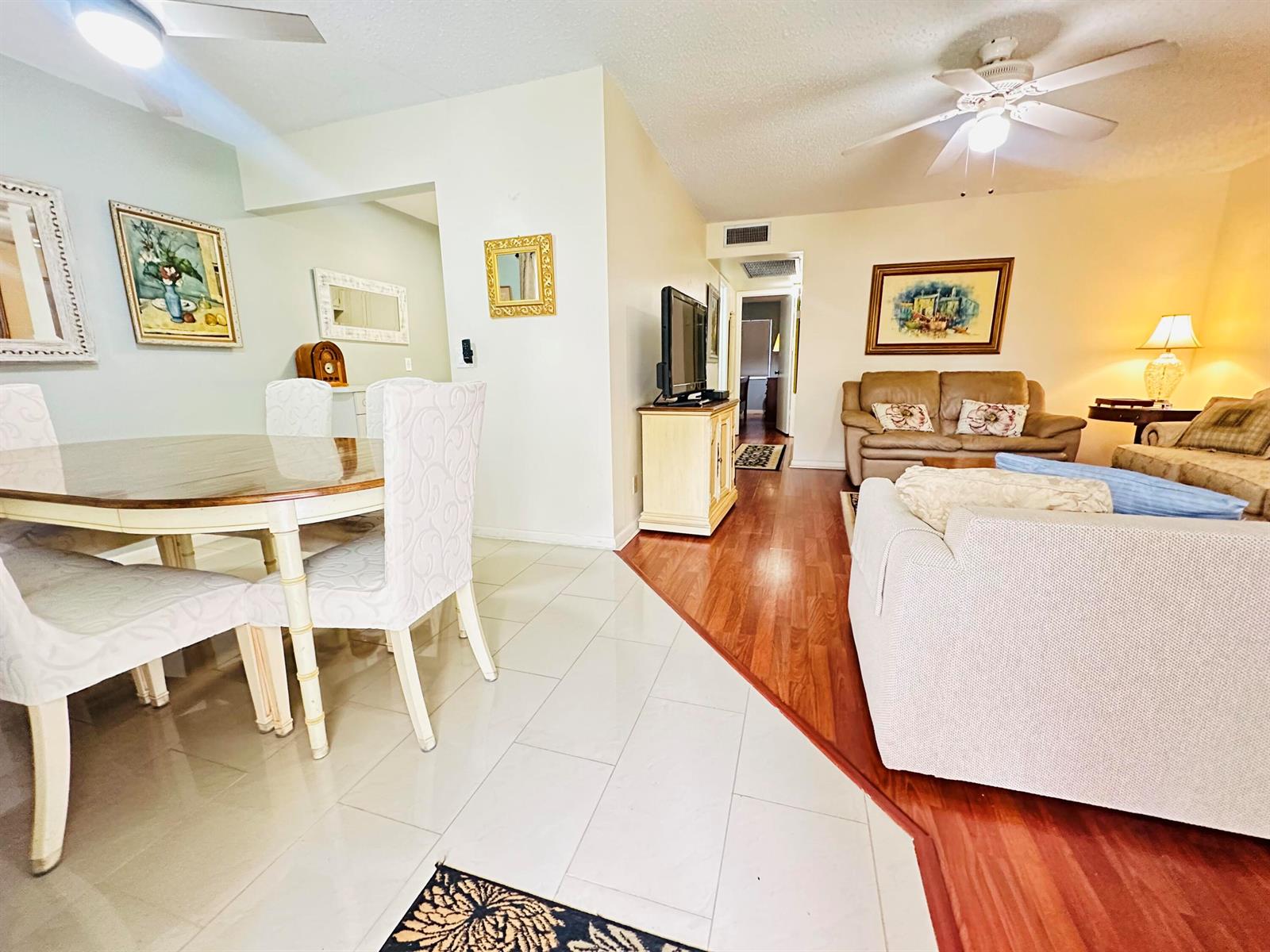 A dining area with tile floors transitions into a living room with wood-look flooring — 174 Durham C, Deerfield Beach FL 33442, DEERFIELD BEACH, FL