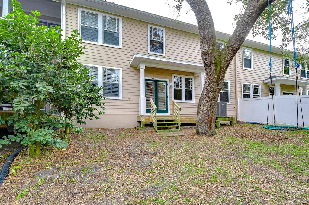 The exterior of a two-story house features beige siding, a small wooden deck, and a swing — 208 ELM VIEW COURT, BRANDON, FL