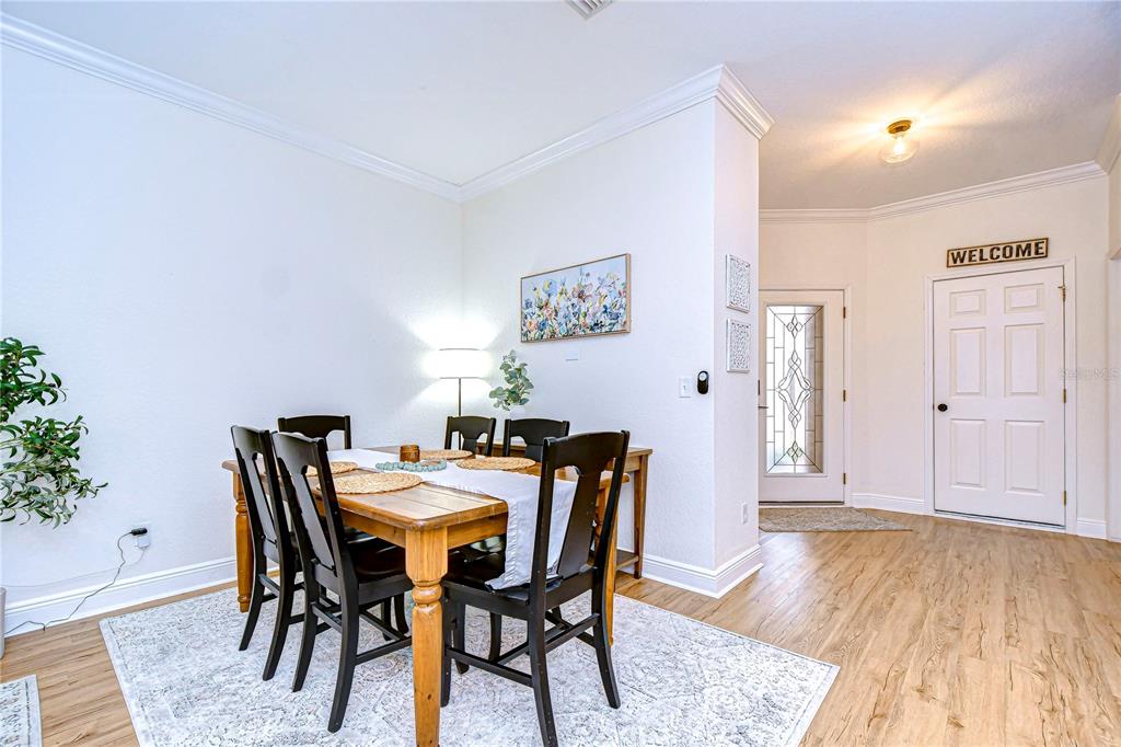 A dining area with a wooden table and chairs sits near an entryway with a door — 208 ELM VIEW COURT, BRANDON, FL