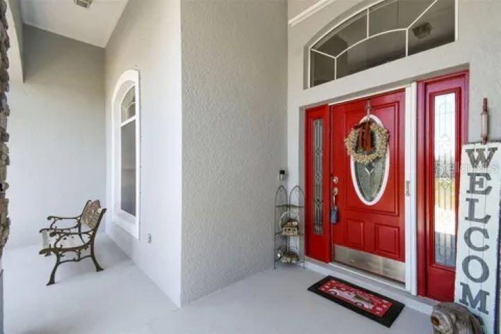 A covered front porch features a red door with sidelights, a bench, and a welcome sign — 1900 GRIFF WOOD COURT, ST CLOUD, FL