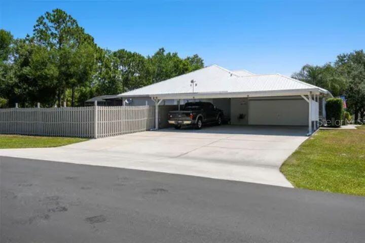 A single-story house features a large attached carport, a concrete driveway, and a fenced yard — 1900 GRIFF WOOD COURT, ST CLOUD, FL