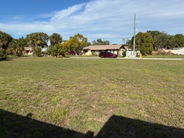 A large, grassy vacant lot sits in front of a residential street with houses — 27344 Elkwood Circle, Hudson FL 34667, HUDSON, FL