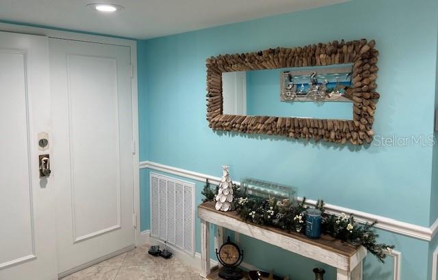 An entryway features light blue walls, a driftwood-framed mirror, and a rustic console table — 1460 GULF BOULEVARD UNIT 1105, CLEARWATER BEACH, FL