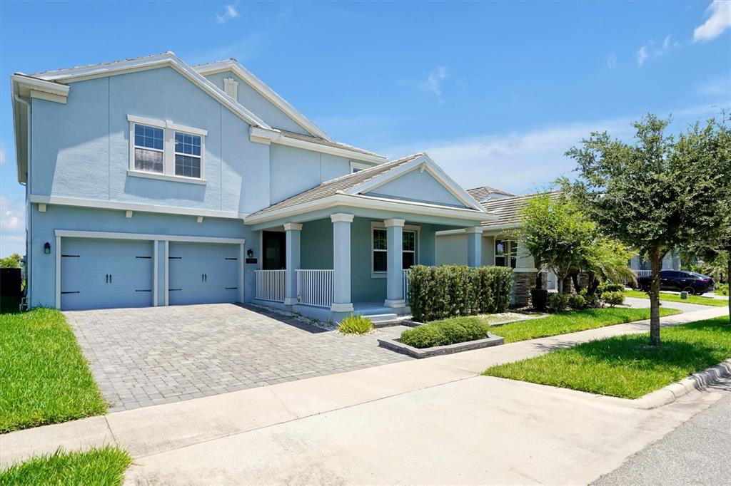 A two-story light blue house with a paved driveway, a front porch, and a garage — 12151 IMAGINARY WAY, ORLANDO, FL