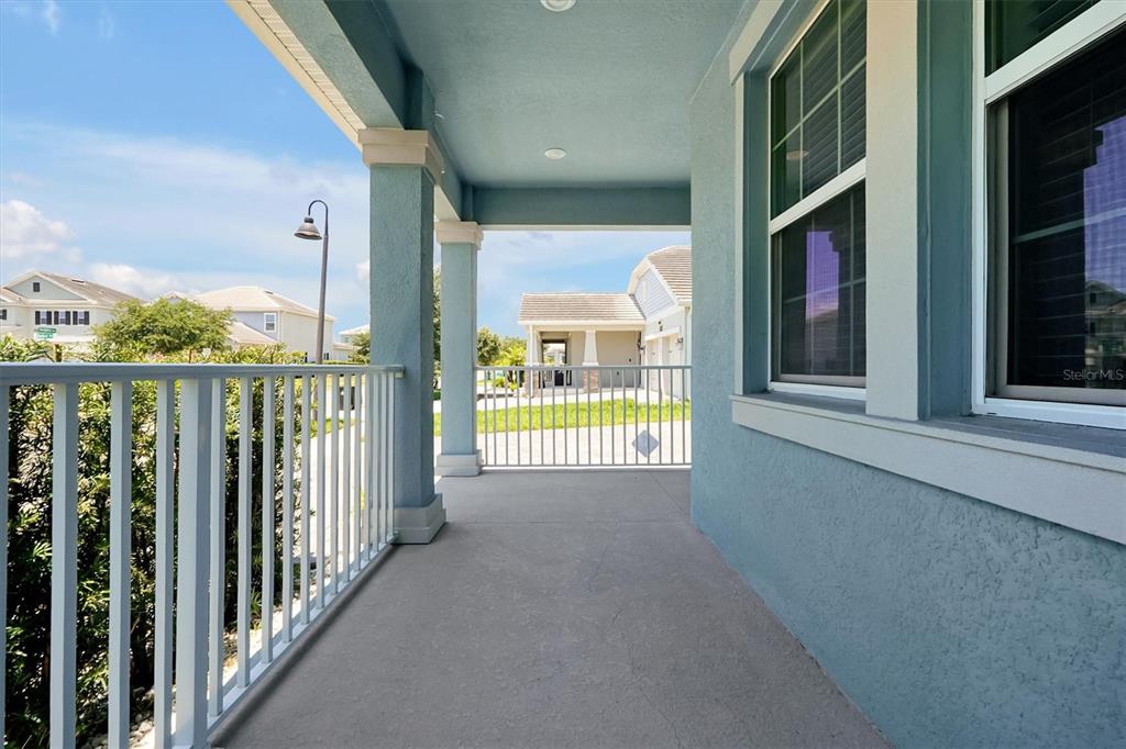 A covered porch with blue walls, white railings, and a concrete floor overlooks a neighborhood — 12151 IMAGINARY WAY, ORLANDO, FL