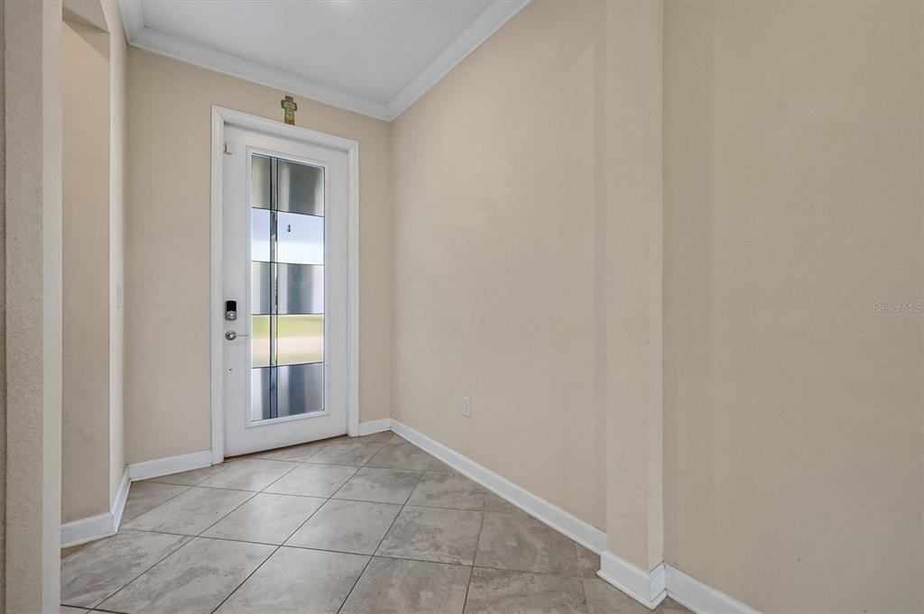 An entryway features light-colored walls, tile flooring, and a white front door with glass panels — 12151 IMAGINARY WAY, ORLANDO, FL