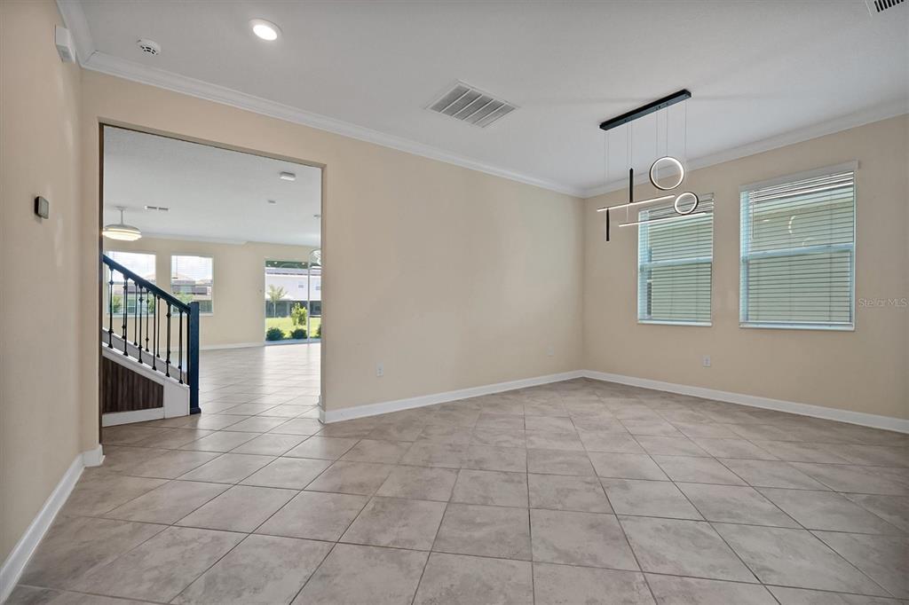 An empty room with tile flooring, a modern light fixture, and a view of stairs — 12151 IMAGINARY WAY, ORLANDO, FL