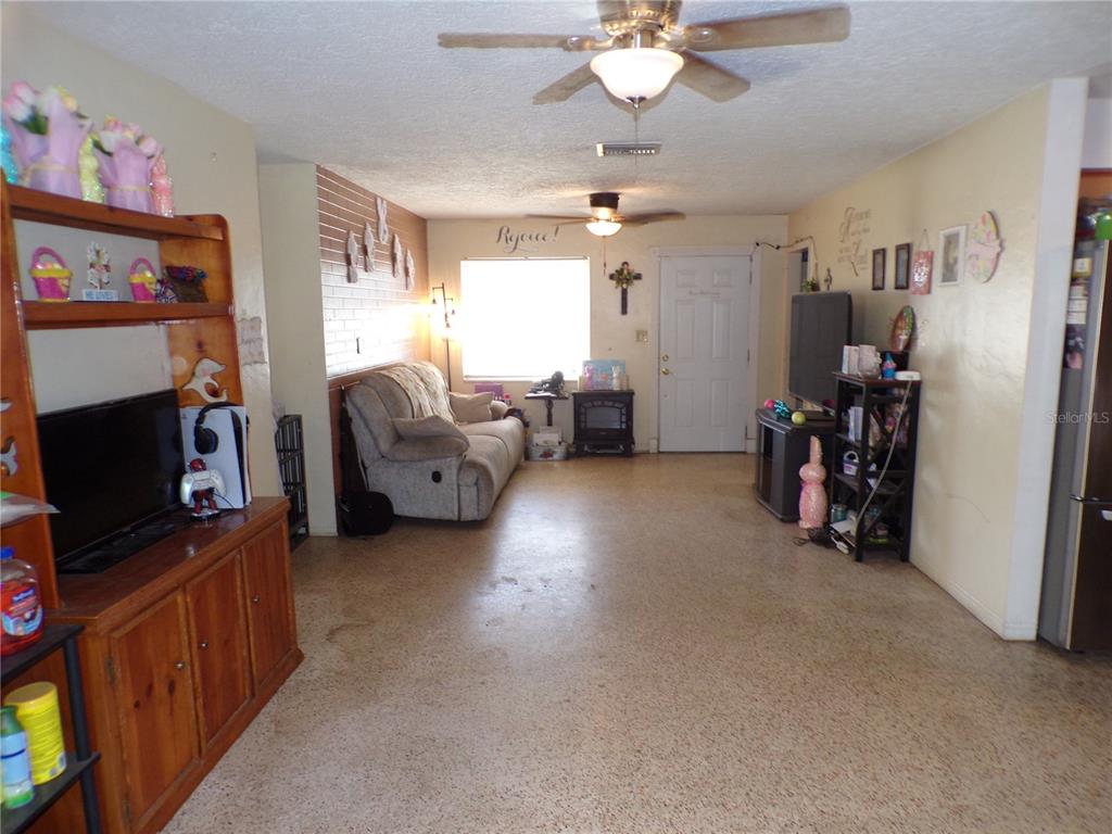 A living room features a beige sofa, a wood entertainment center, and a ceiling fan — 5606 87TH AVENUE N, PINELLAS PARK, FL