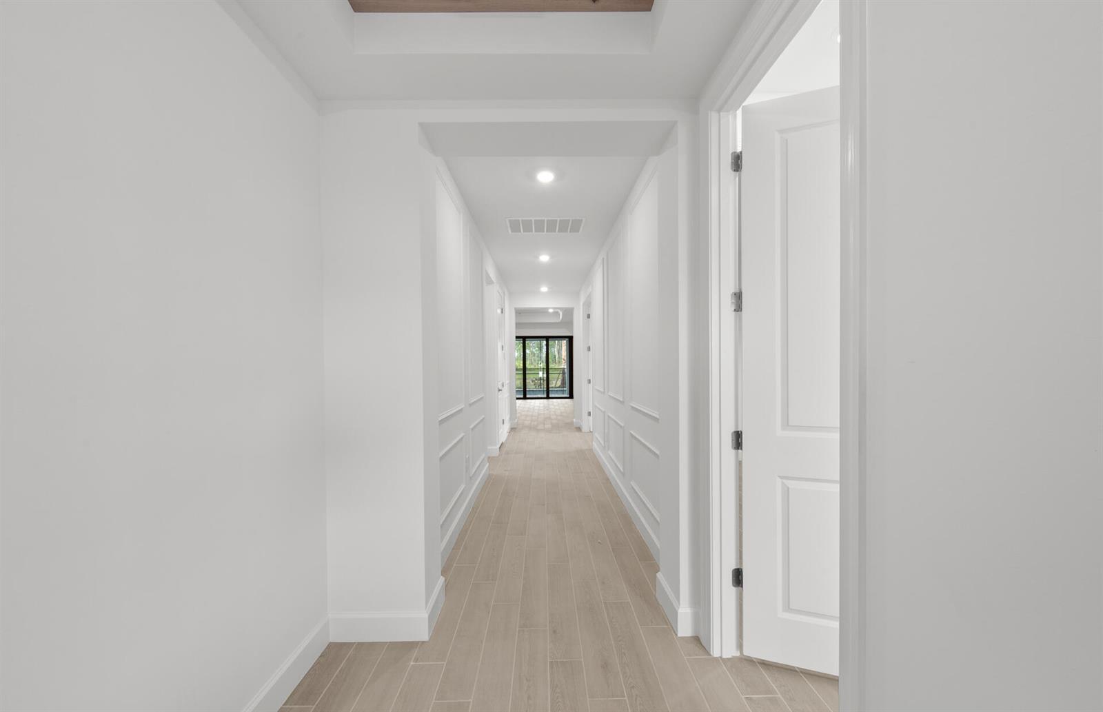A long white hallway features wainscoting, light wood-look tile flooring, and recessed ceiling lighting — 2034 Terreno Boulevard, Naples FL 34120, NAPLES, FL