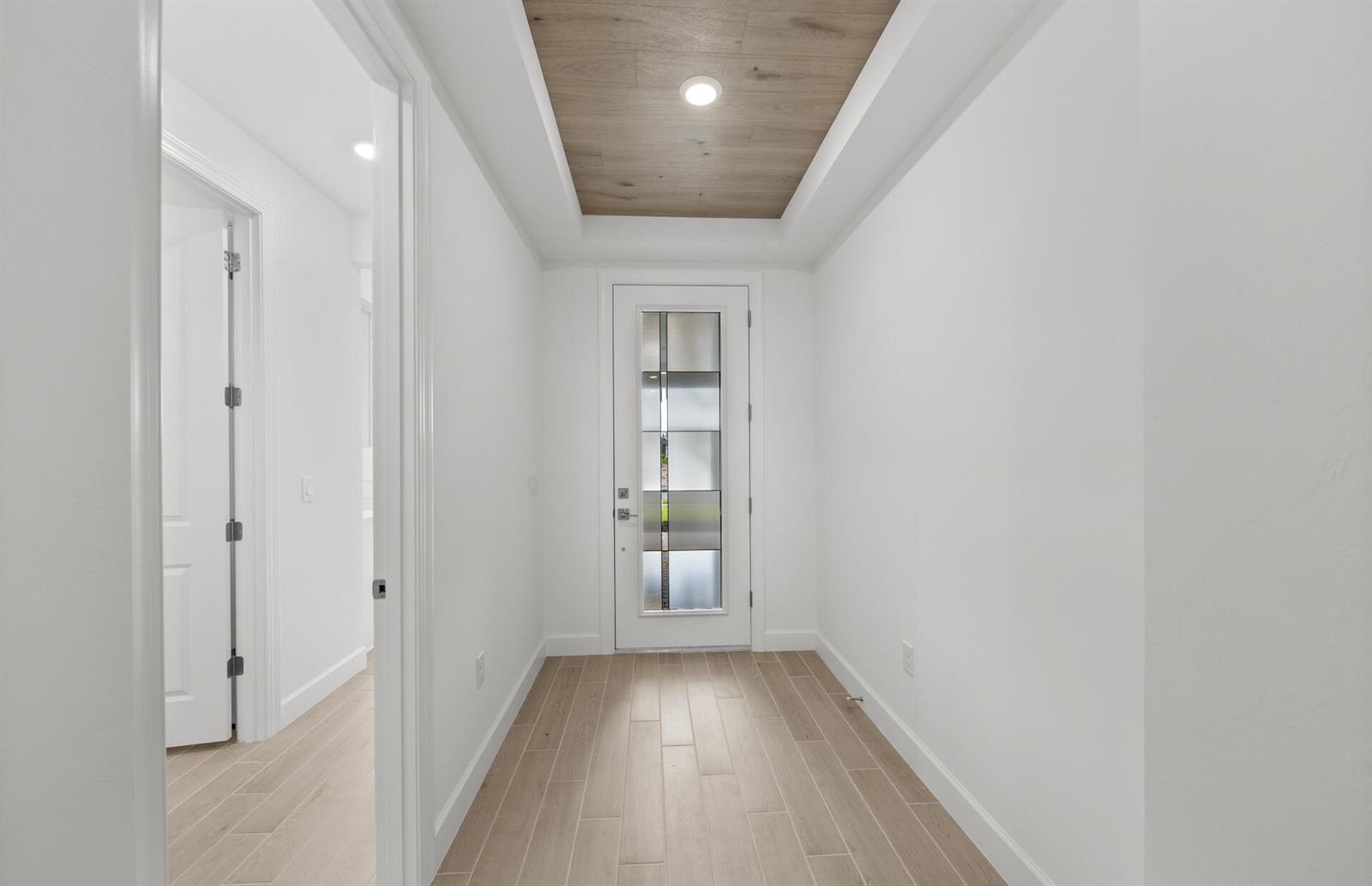 A bright entryway features a wood-paneled tray ceiling, light tile flooring, and a glass-paneled door — 2034 Terreno Boulevard, Naples FL 34120, NAPLES, FL