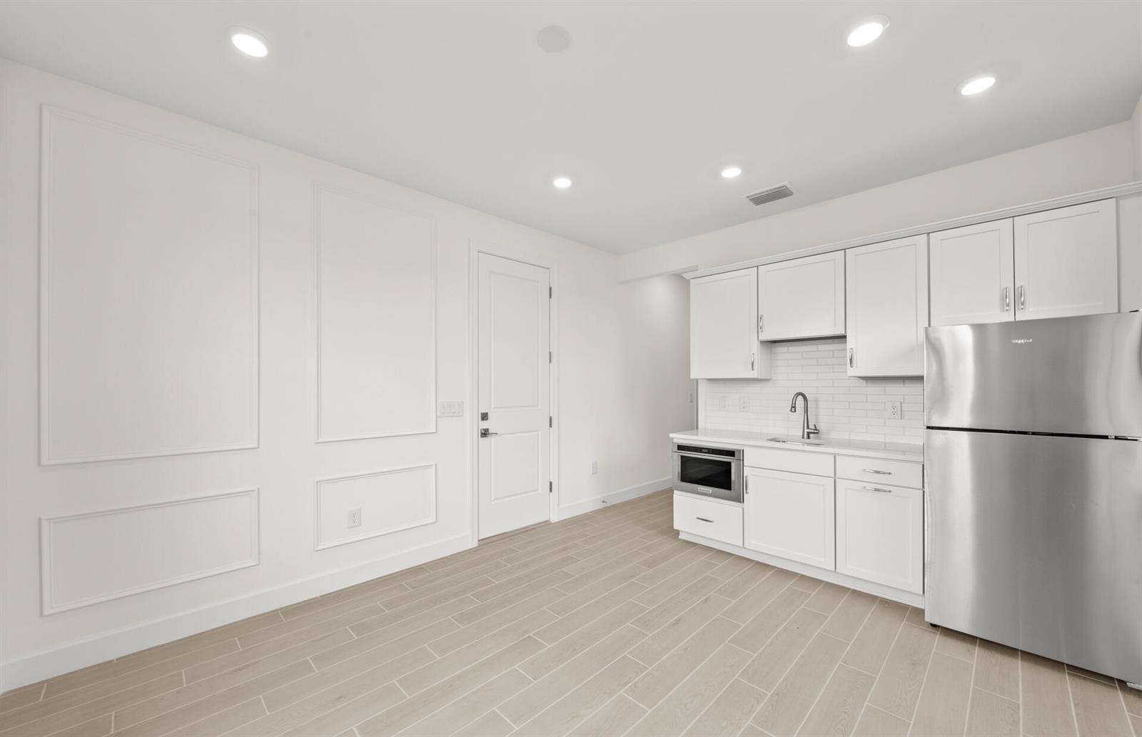 A kitchen area with white cabinets, stainless steel appliances, and light wood-look tile flooring — 2034 Terreno Boulevard, Naples FL 34120, NAPLES, FL