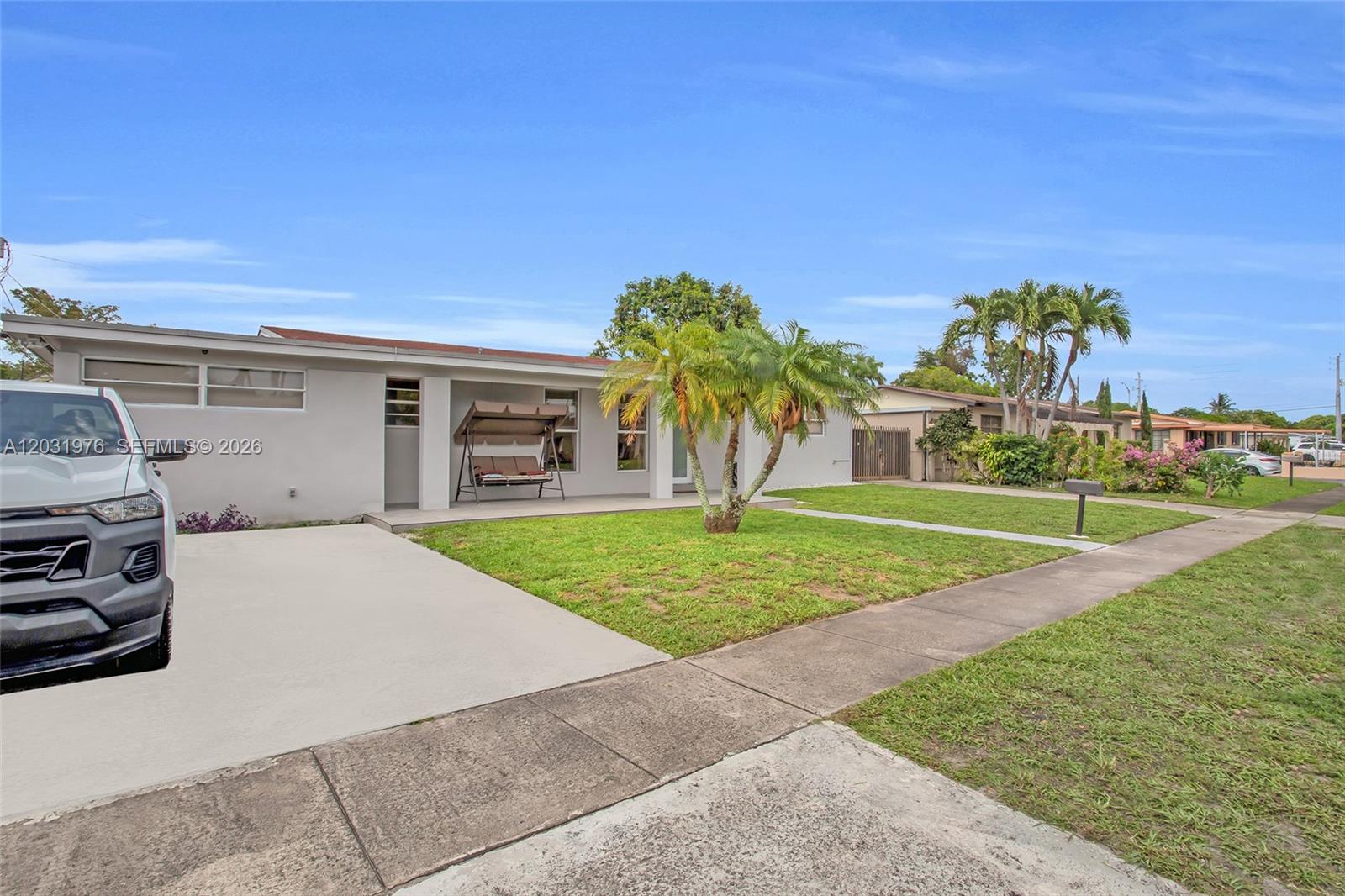A single-story house with a concrete driveway, a front porch swing, and a palm tree — 855 W 70th Pl, Hialeah FL 33014, HIALEAH, FL