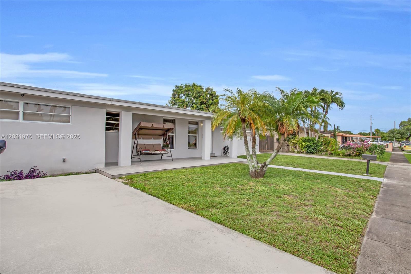 A single-story house features a concrete driveway, a front porch with a swing, and landscaping — 855 W 70th Pl, Hialeah FL 33014, HIALEAH, FL